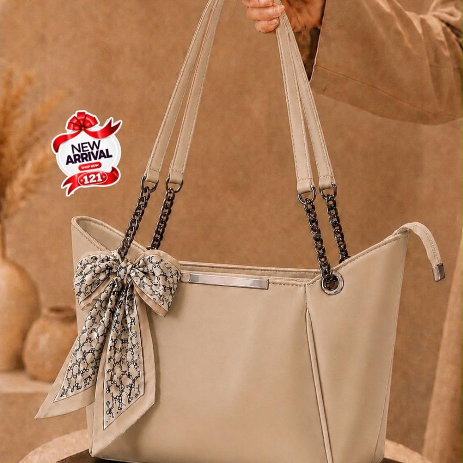 beige tote bag with a large matching fabric bow and patterned scarf detai