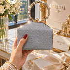 glittery clutch bag with a gold-tone ring handle encrusted with clear rhinestones